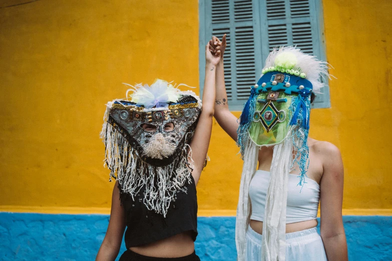 two girls wearing masquetes with one holding his hand up to the sky