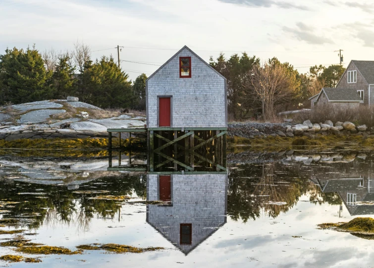 there is an old white boathouse that sits at the water's edge