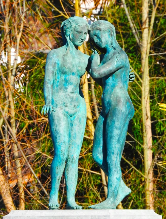 two statues are standing next to each other near trees