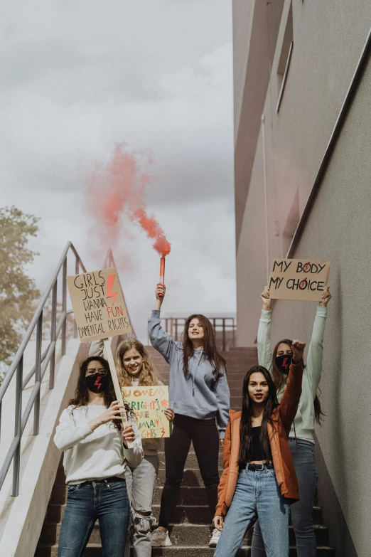 group of young women standing on stairs holding up signs