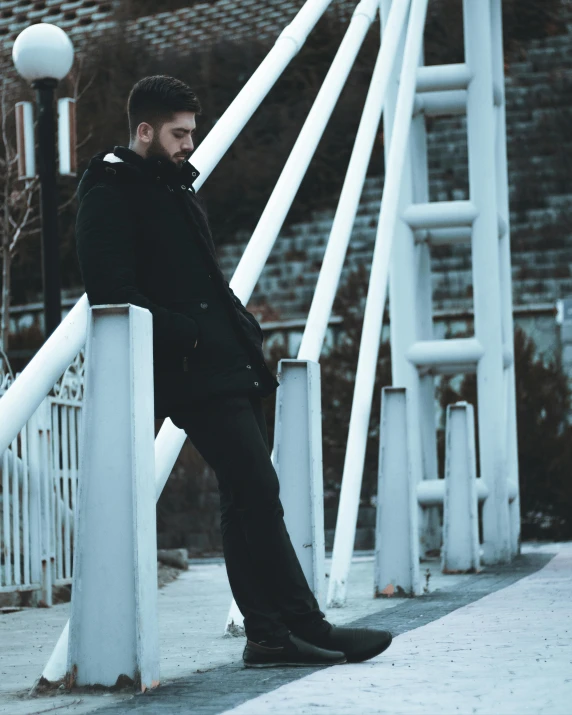 a man sitting on top of white railing near a fence