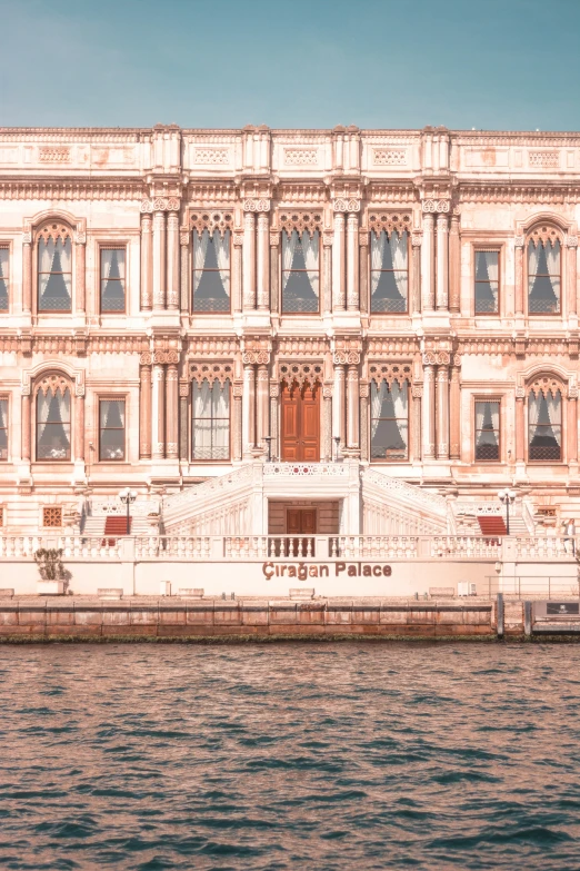 the building is beige with windows on it and a boat passing by