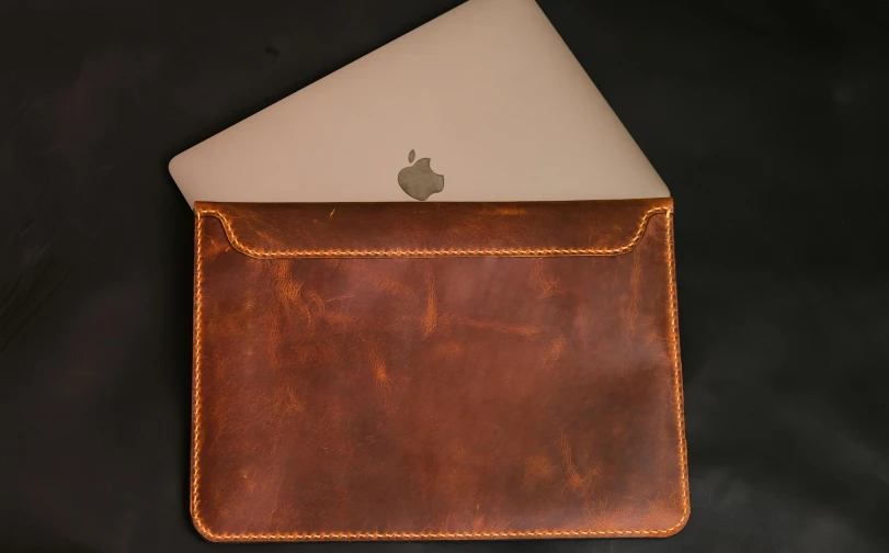 an apple computer sits inside of a leather case