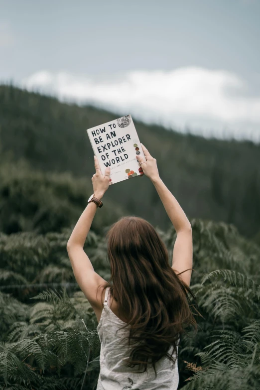 a person holding a book with a mountain in the background