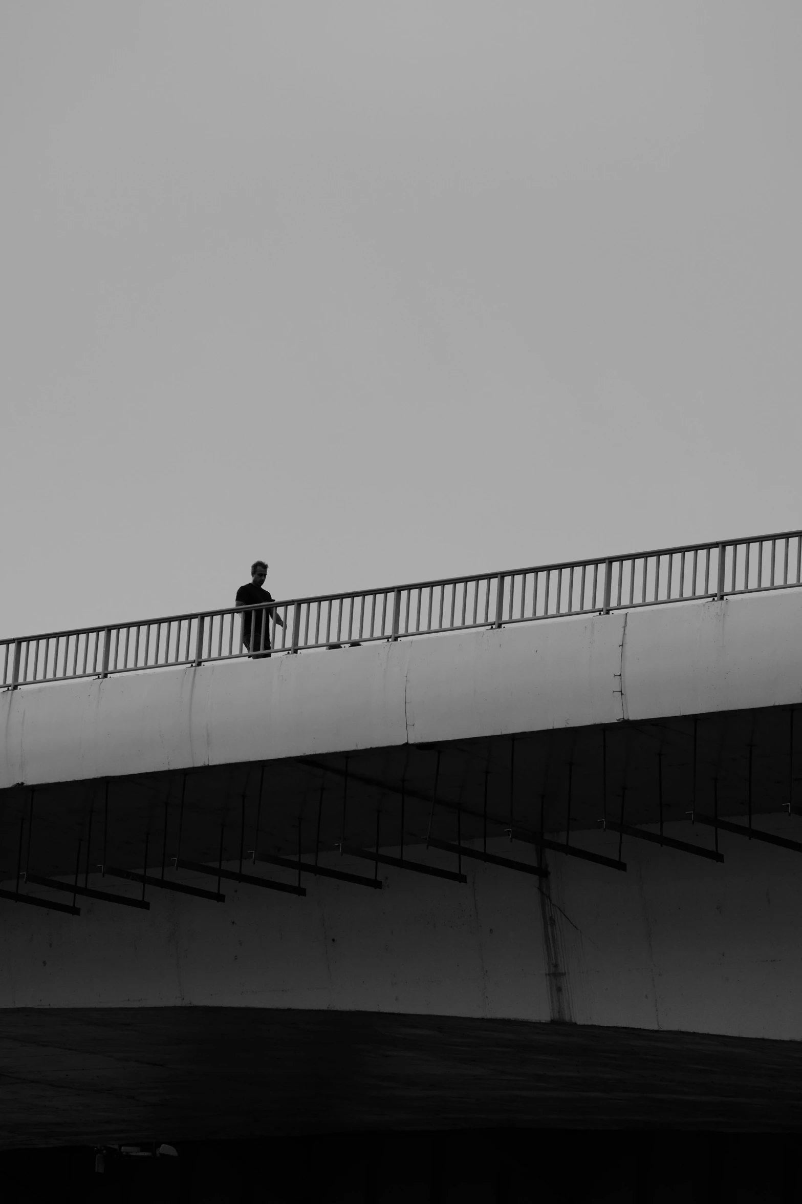 a man walking down the side of a bridge over water