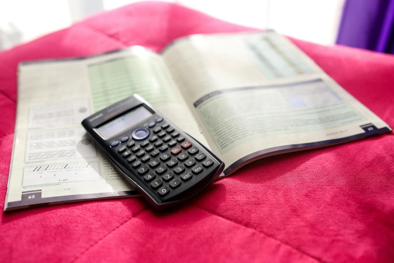 an open book and calculator on the bed