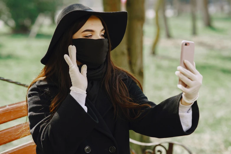 a woman wearing a mask taking a selfie on her cell phone