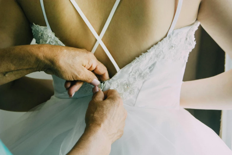 someone holding their wedding dress, adjusting it to tie