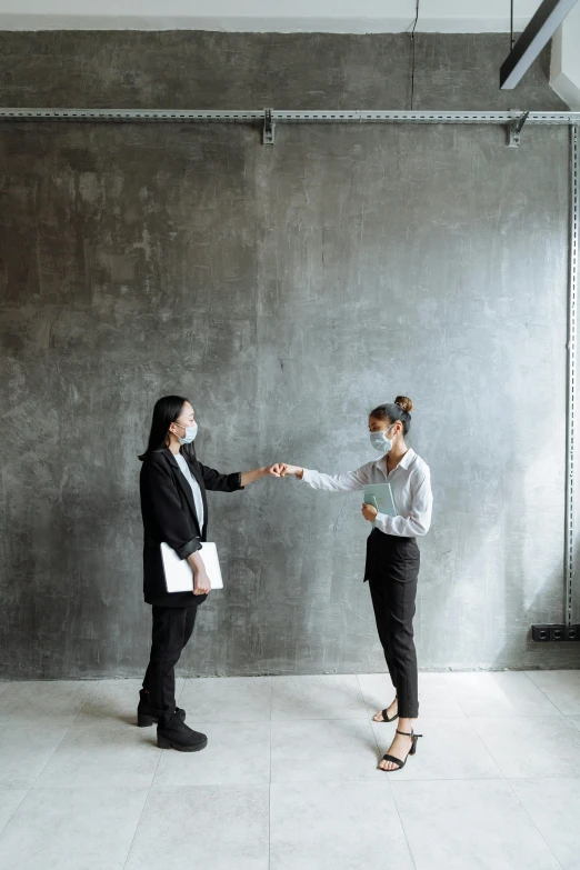 a man and woman shake hands in front of a wall