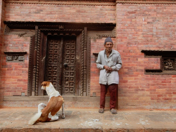 there is a man standing near a dog and another is waiting