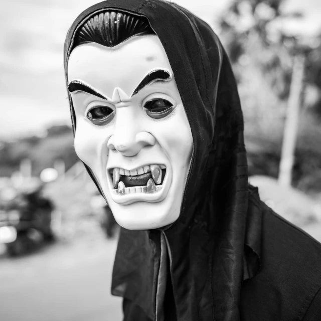 man with face mask and hood with mouth open on sidewalk