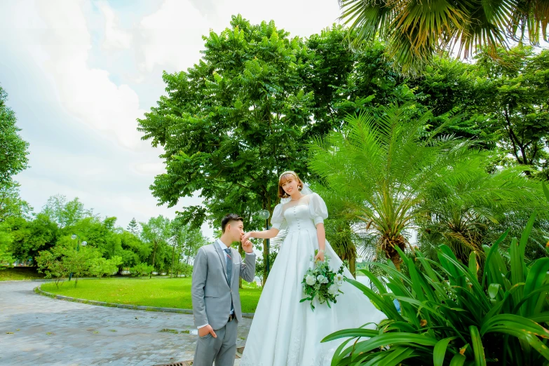 a bride and groom standing in the middle of the park