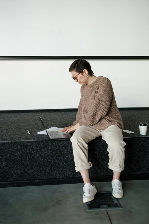 a woman is sitting on top of a counter with a laptop