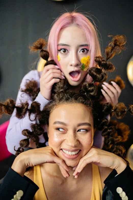 two girls standing side by side and one has yellow on her nose