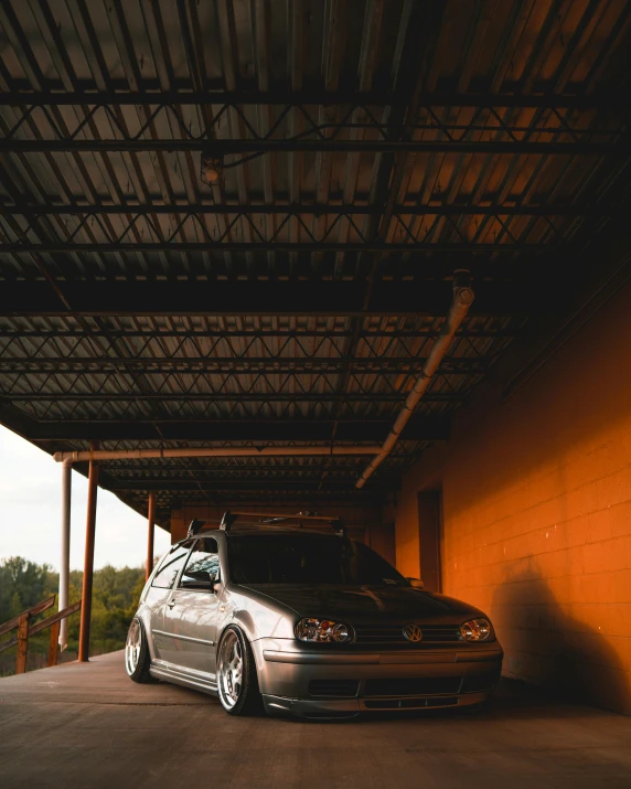 a white sedan is parked under a roof in a parking garage