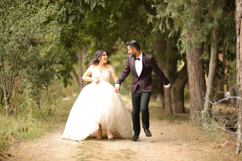 a couple in wedding dress walking through the woods