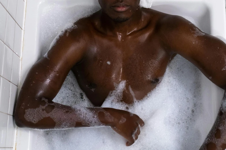 a man wearing  is in the tub filled with soap