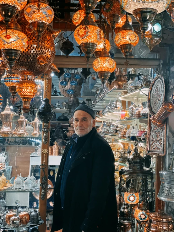 an older man stands in front of a display of lamps and vases