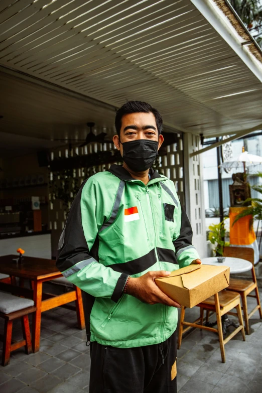 a man standing outside with boxes wearing a mask