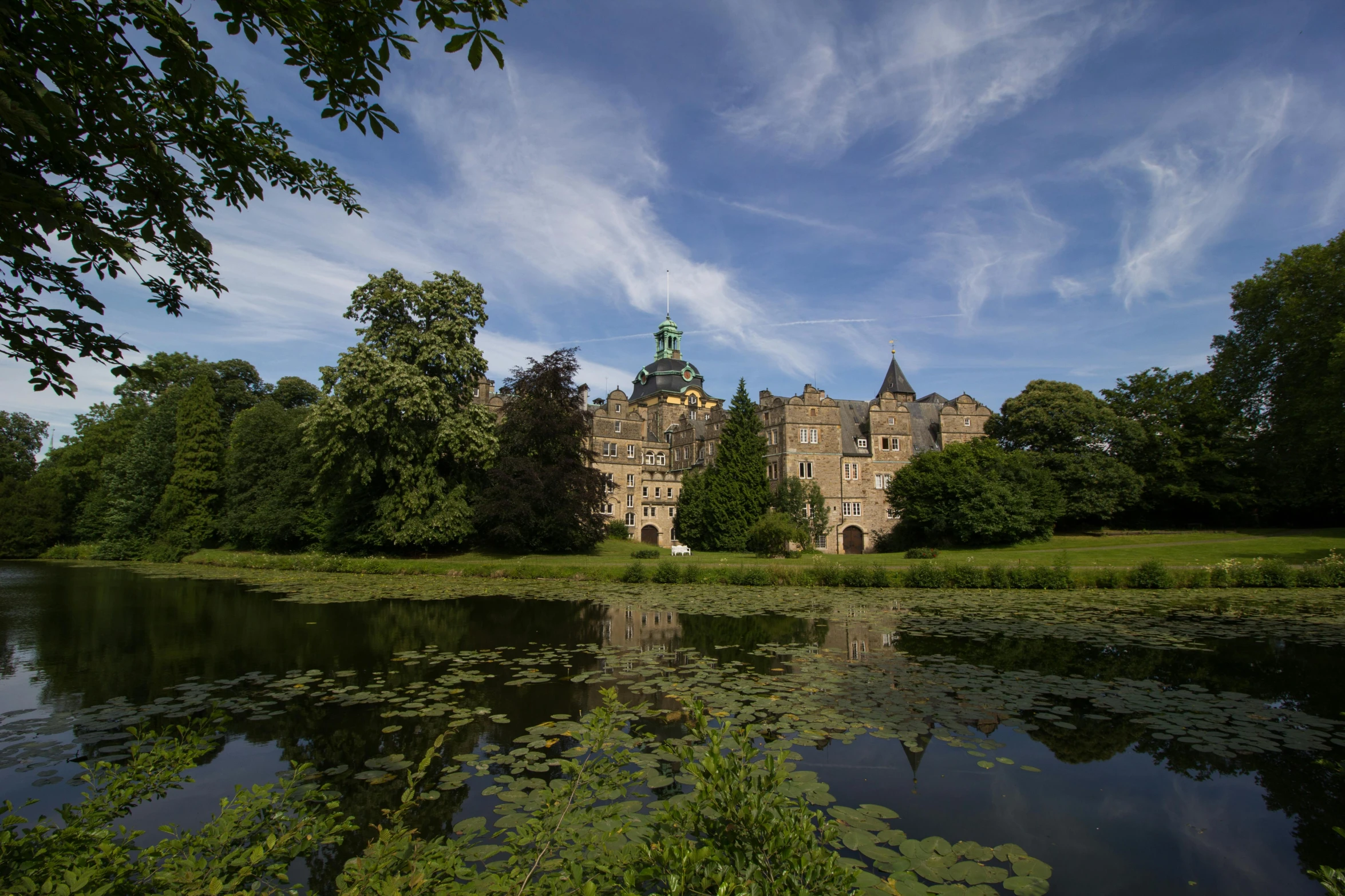 there is a large building near the water and trees