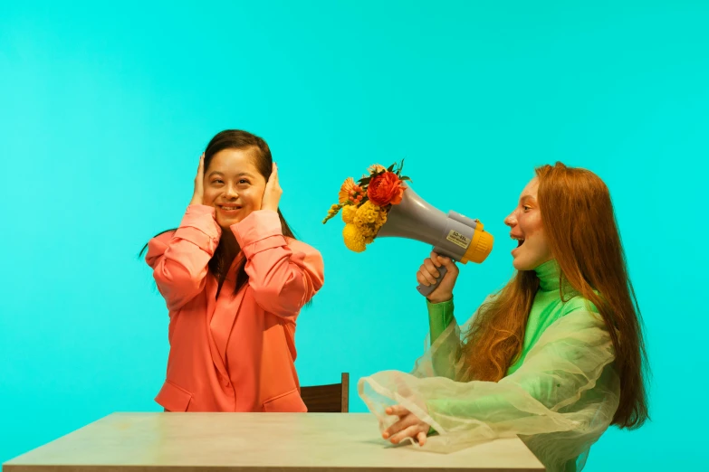 two woman standing next to each other on a table with a blow dryer