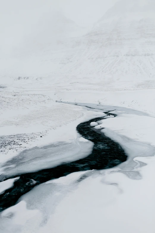 snow - covered land and stream in middle of snowy field