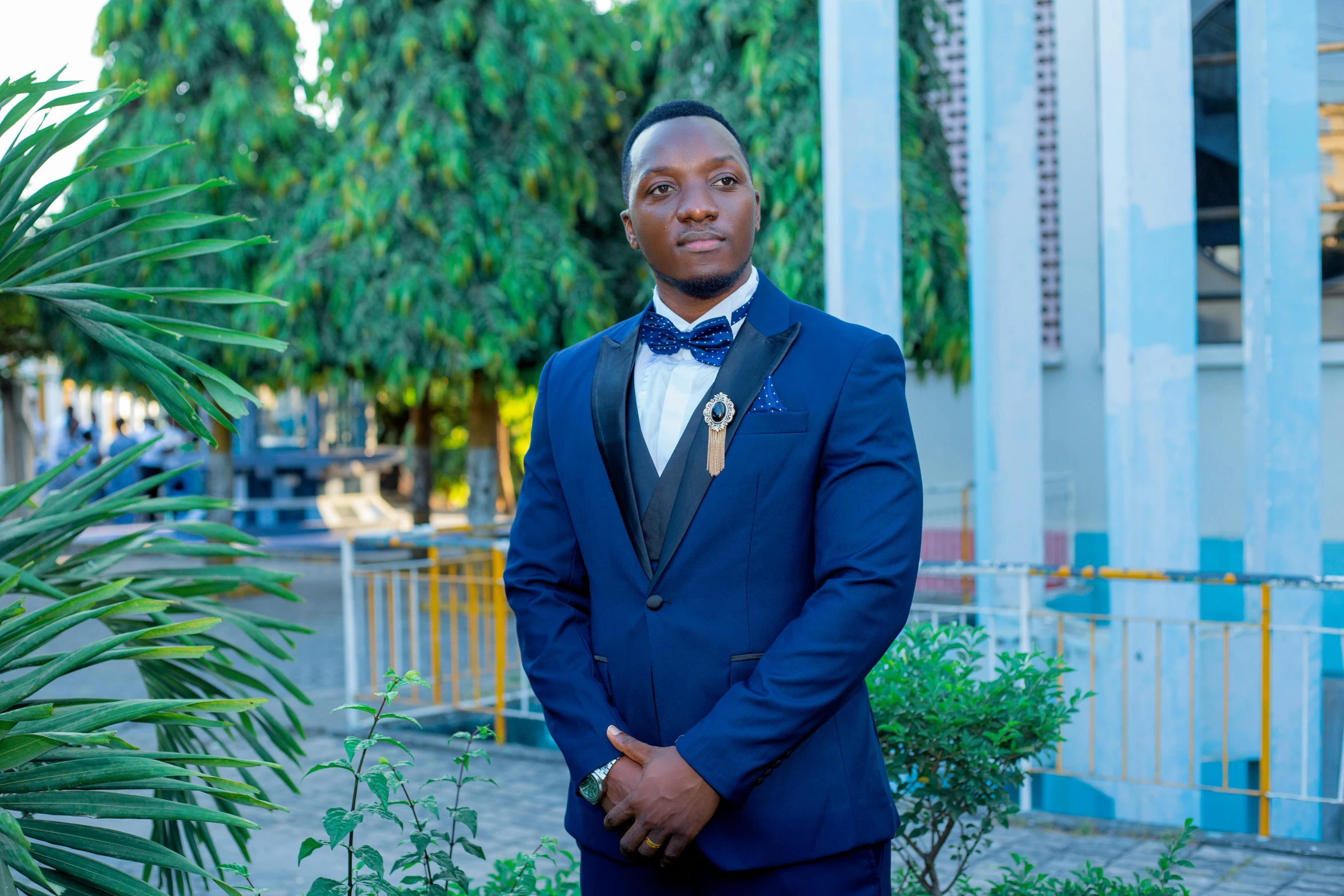 a man in a suit and tie in front of palm trees