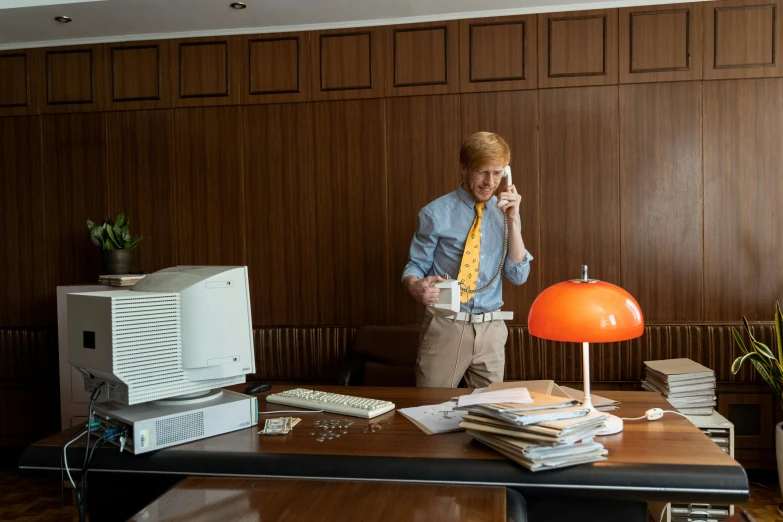 a man is talking on the telephone while using his computer