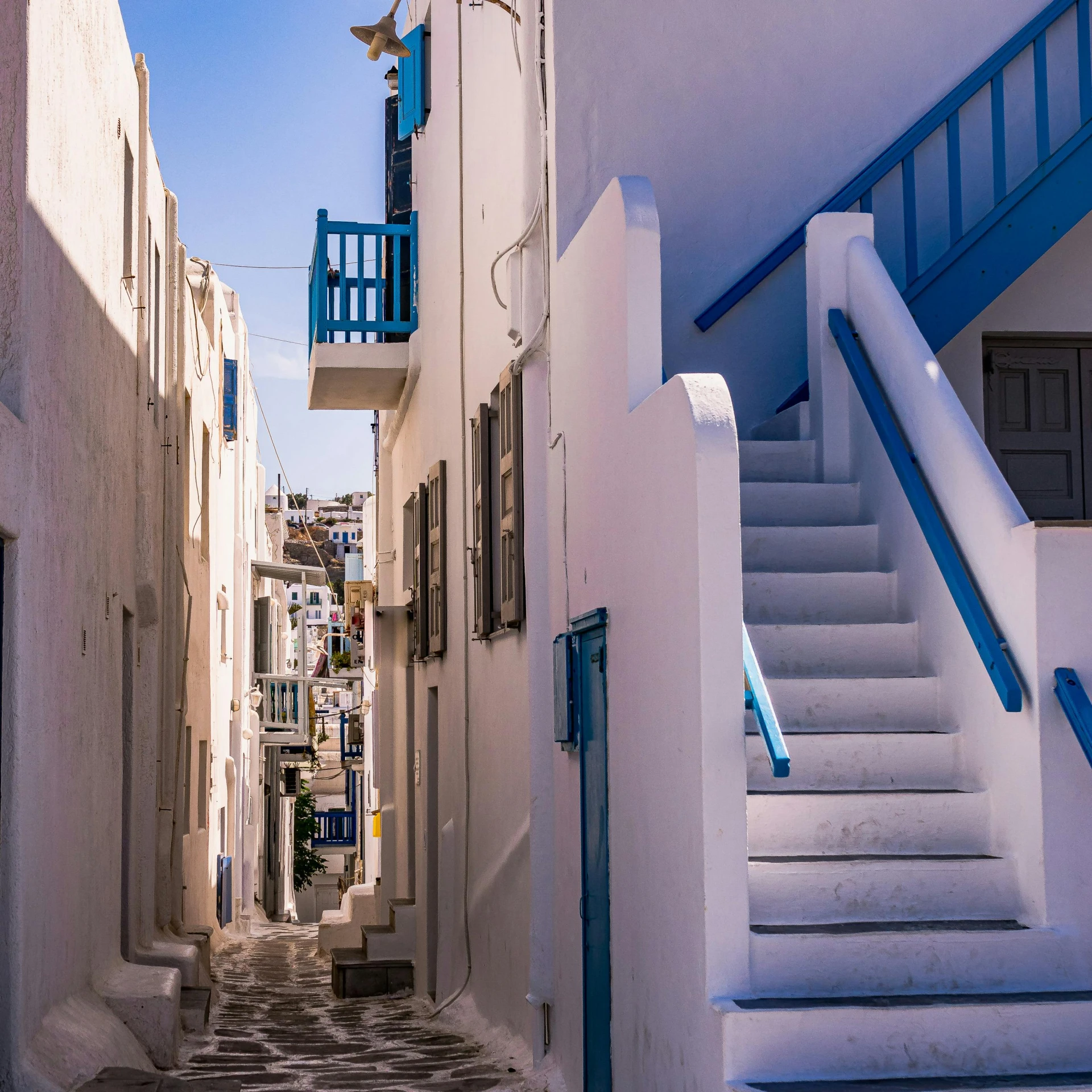 narrow white alleyway in an old village under blue and white balconies