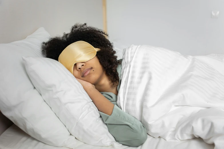 a woman in a bed with a blindfold covering her eyes