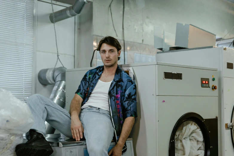 the man is sitting on top of his washer and posing