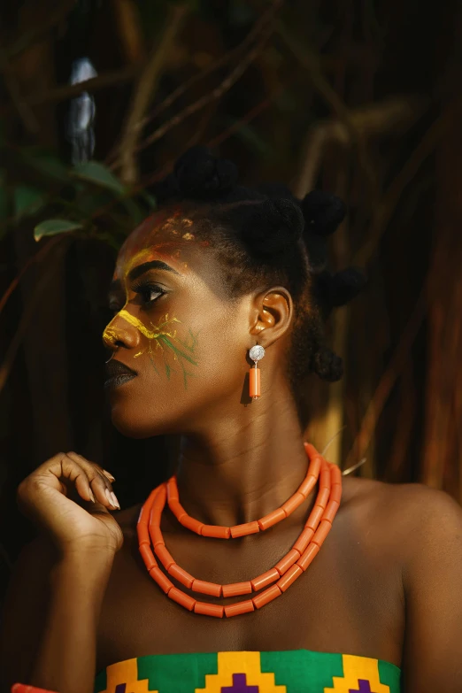 a woman with an artistic make - up and beaded necklace standing in a jungle