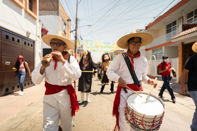 people in red and white traditional outfits standing on a street holding instruments