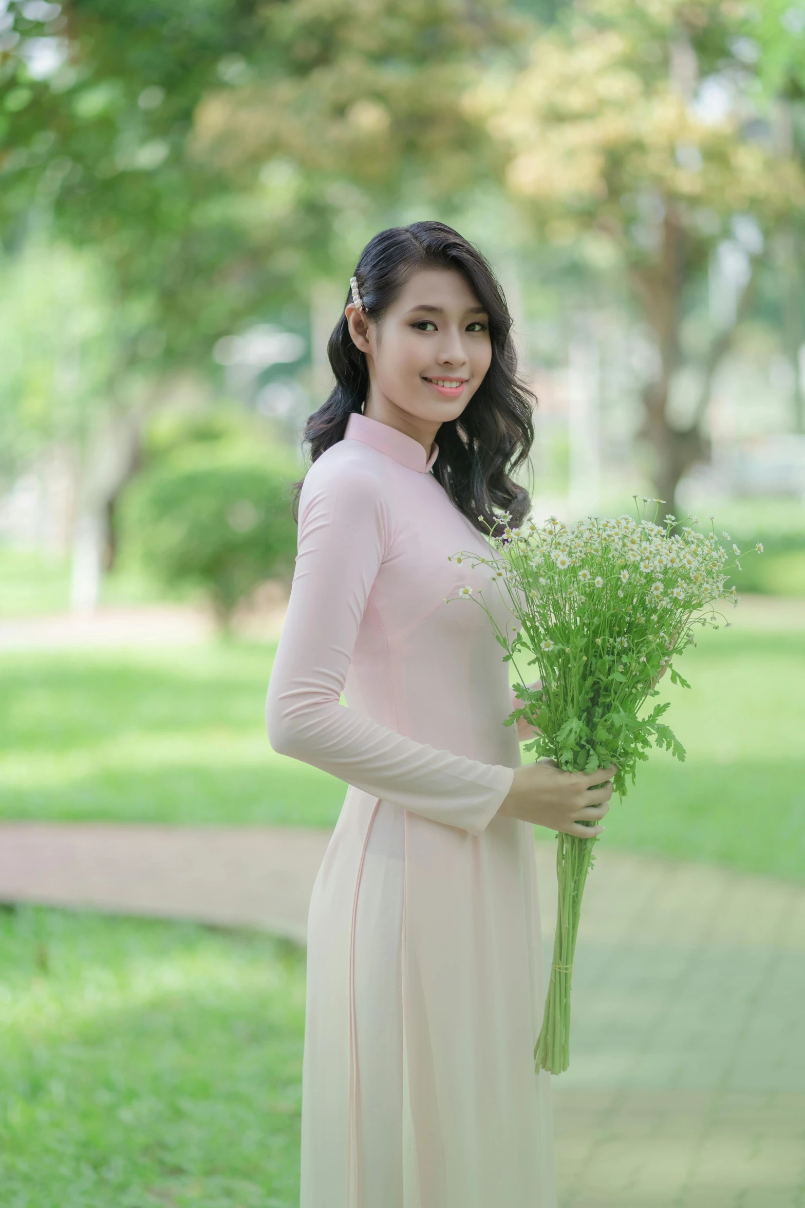 a woman holds flowers in front of her while she stands on the sidewalk