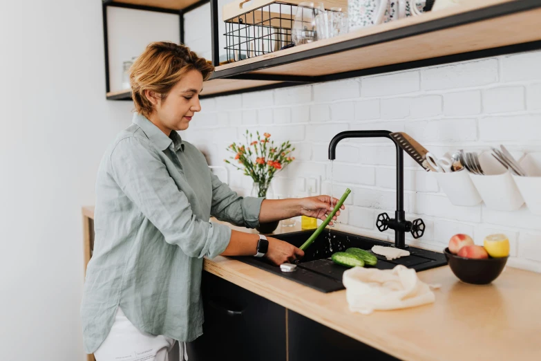 the woman in the kitchen is washing vegetables