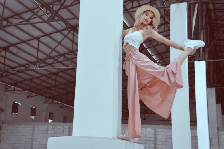 woman wearing pink and white leaning against a pillar