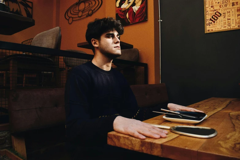 a young man sitting at a table with a smart phone