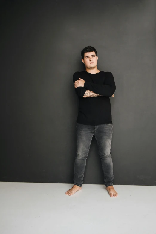 a man posing for a po wearing jeans and a sweater