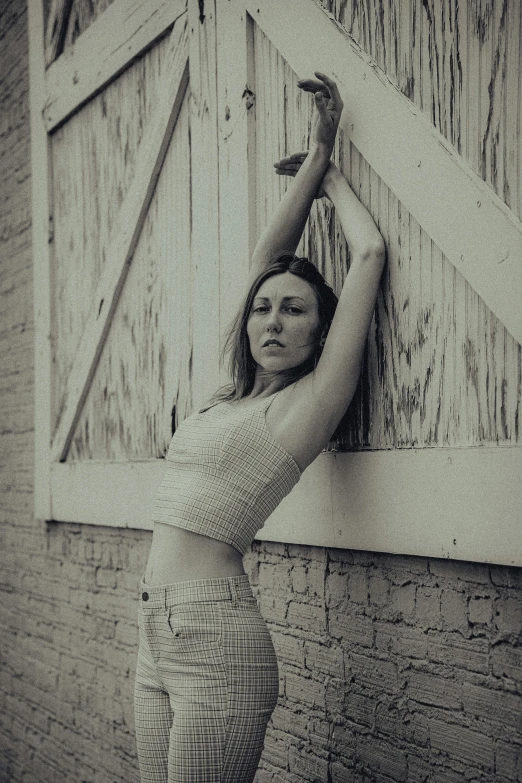 a woman standing and posing behind an wooden barn door