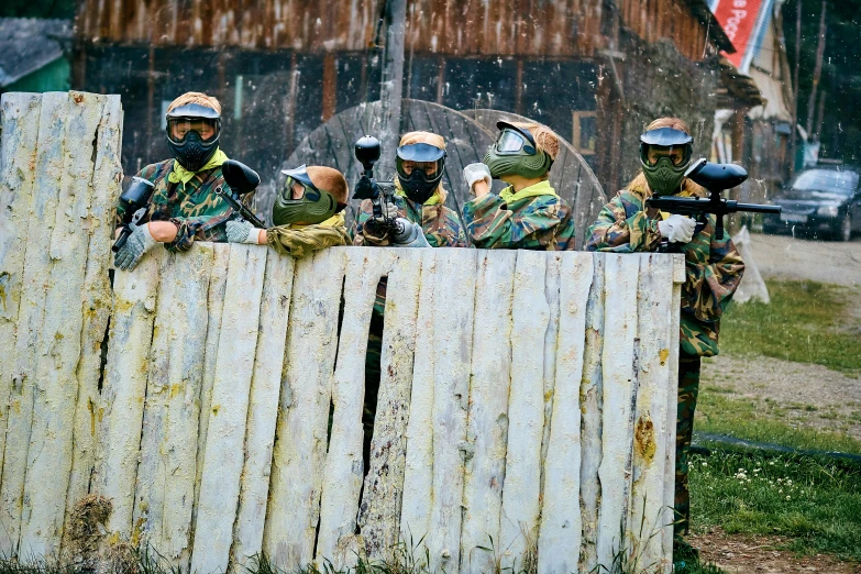 a group of paintball players look over the fence