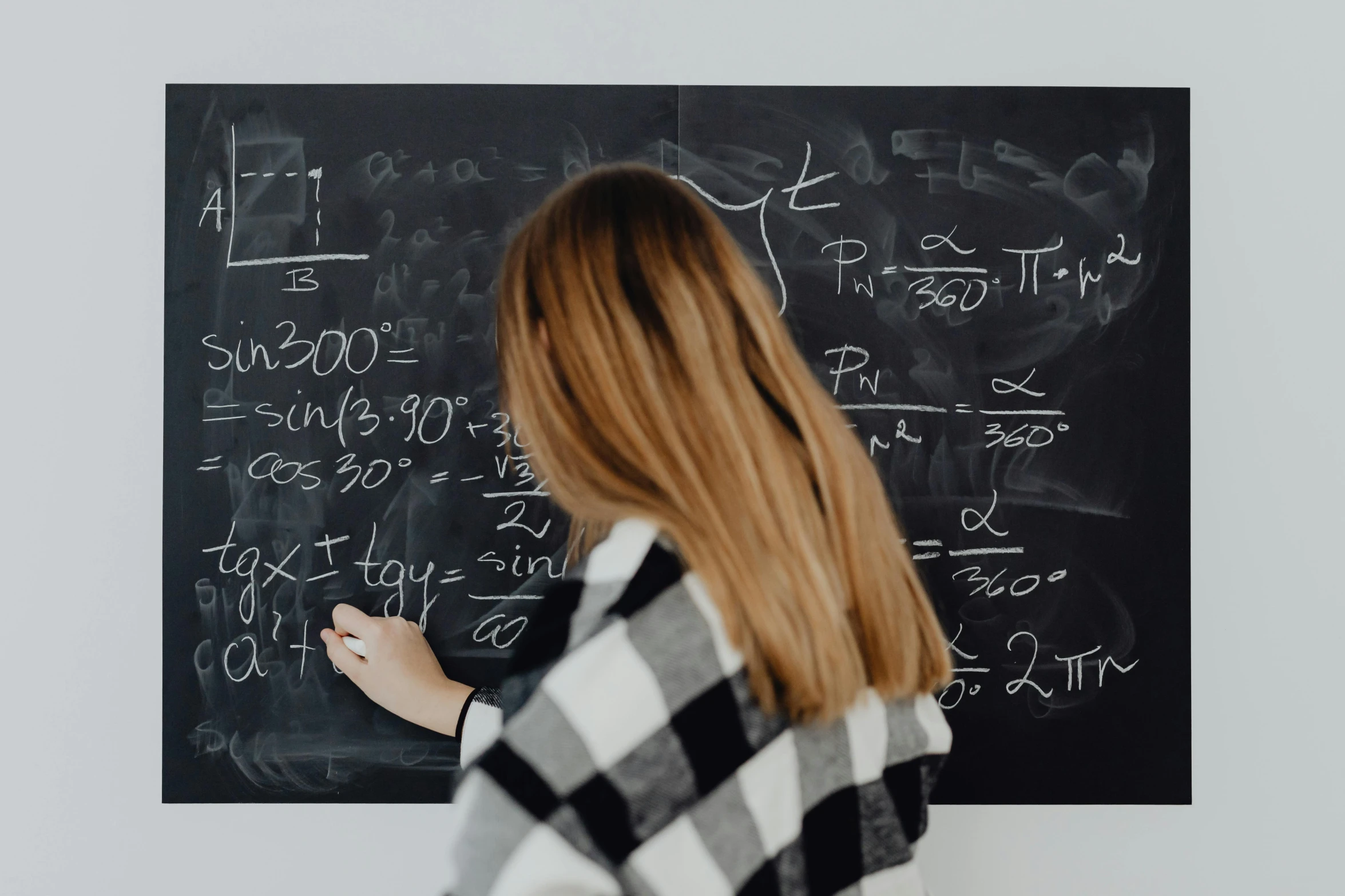 a person writes on a blackboard while pointing it at a white wall