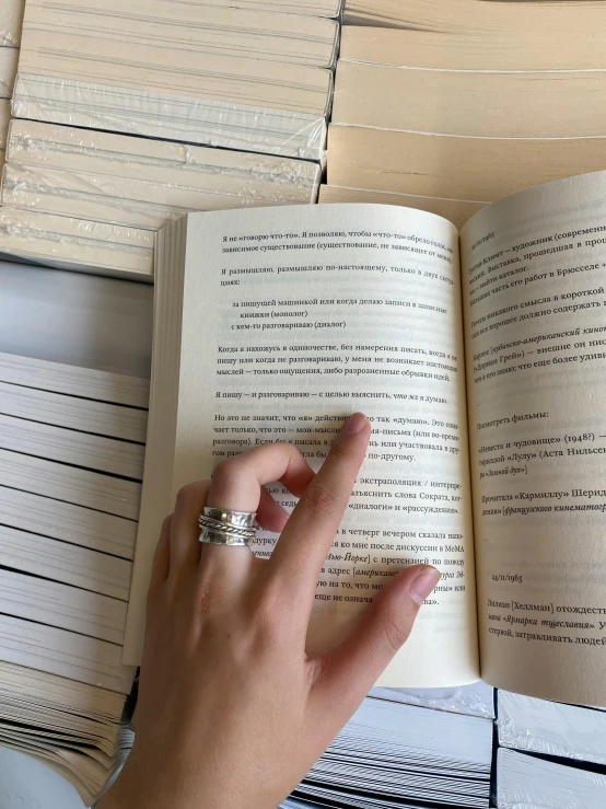 a person holding up a book with their finger