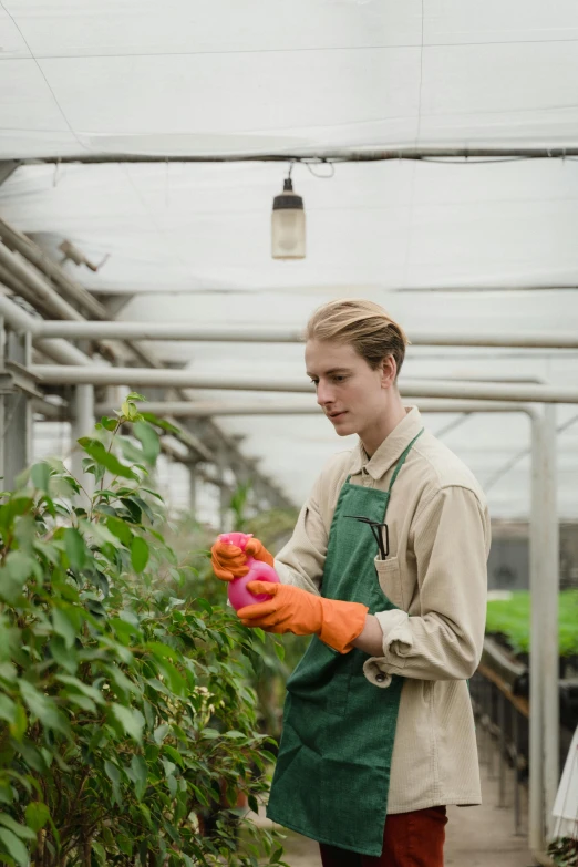 a man is holding an item and standing in a greenhouse