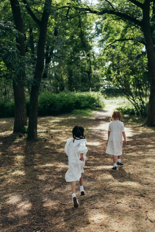 two children are running down a path through the woods