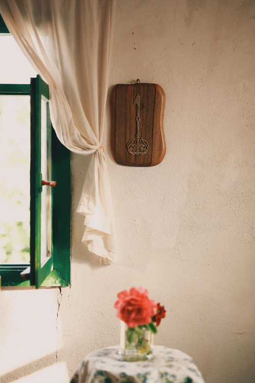 a wooden clock mounted on the wall by a window