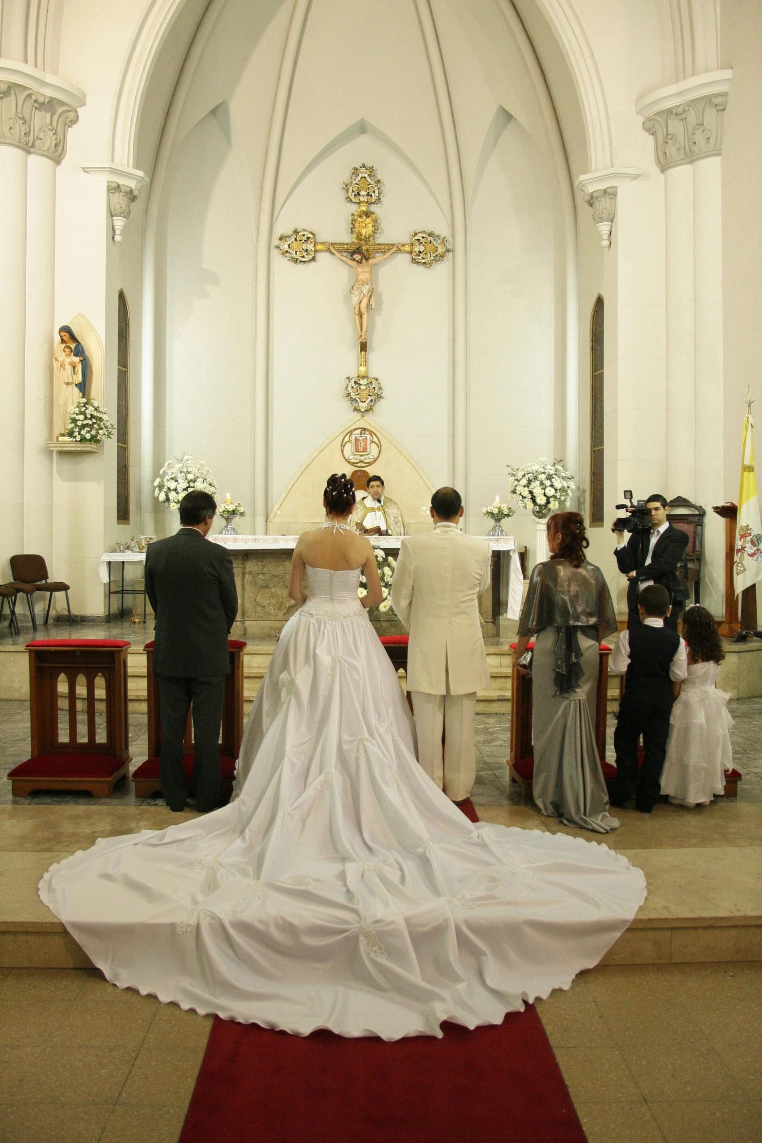 a bride and groom stand in the aisle as a group of people in the pews look on