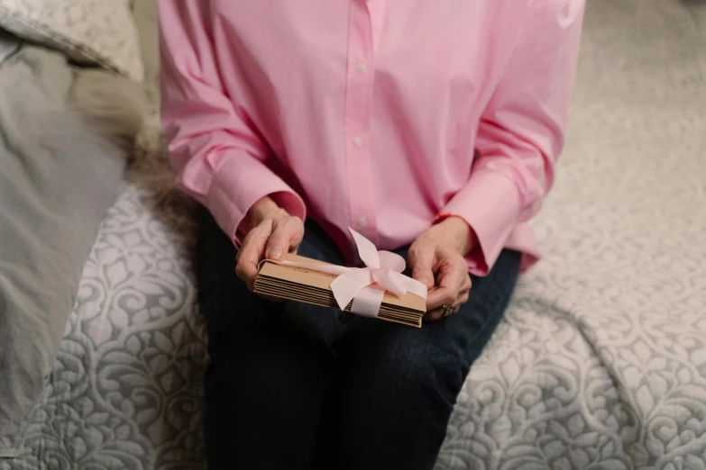 a woman sitting on a couch while wearing a pink shirt