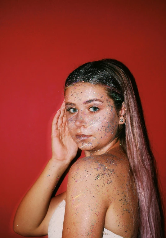 girl with glitter on her face posing with hand near her face