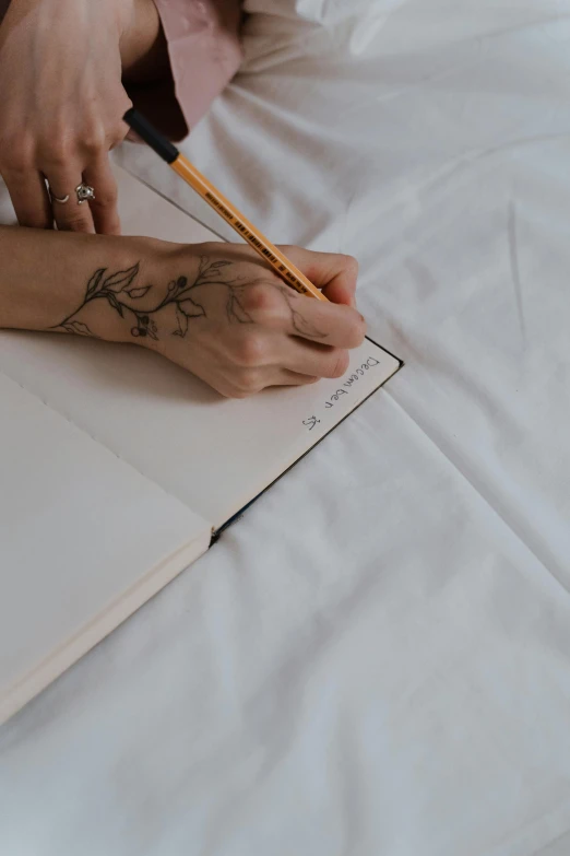 a person writing in an open book with a pencil