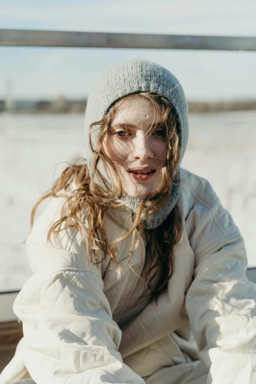 a woman in winter clothing sitting on a ledge